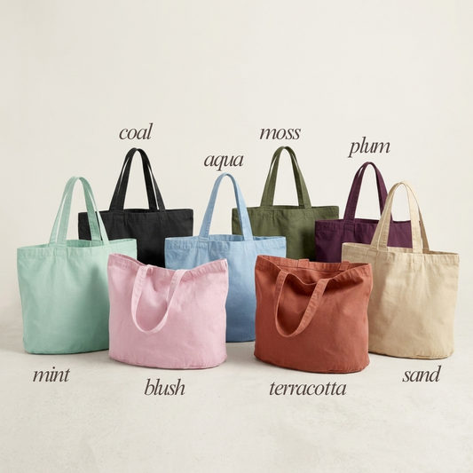 Six canvas tote bags in different colors are arranged in a row against a light beige background, each with its color name printed above and below. The bags are labeled with the names: mint, blush, terracotta, sand, aqua, and plum, with the names 'coal', 'moss', and 'plum' positioned above the respective bags.