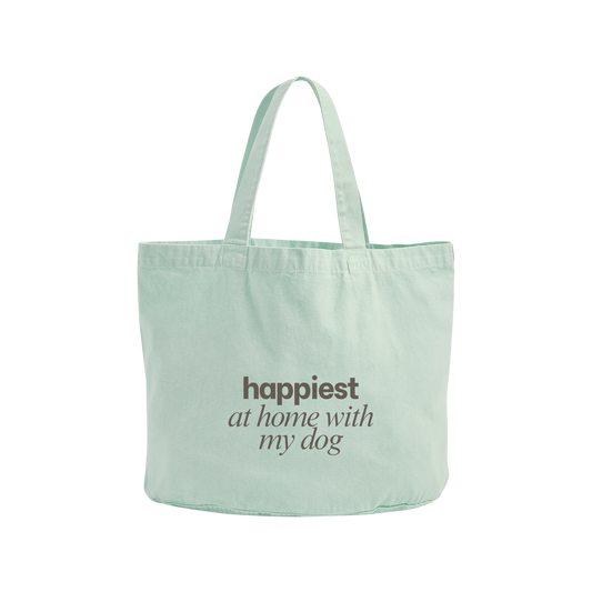 A mint green canvas tote bag with the phrase 'happiest at home with my dog' printed in dark brown text on the front, set against a plain white background.