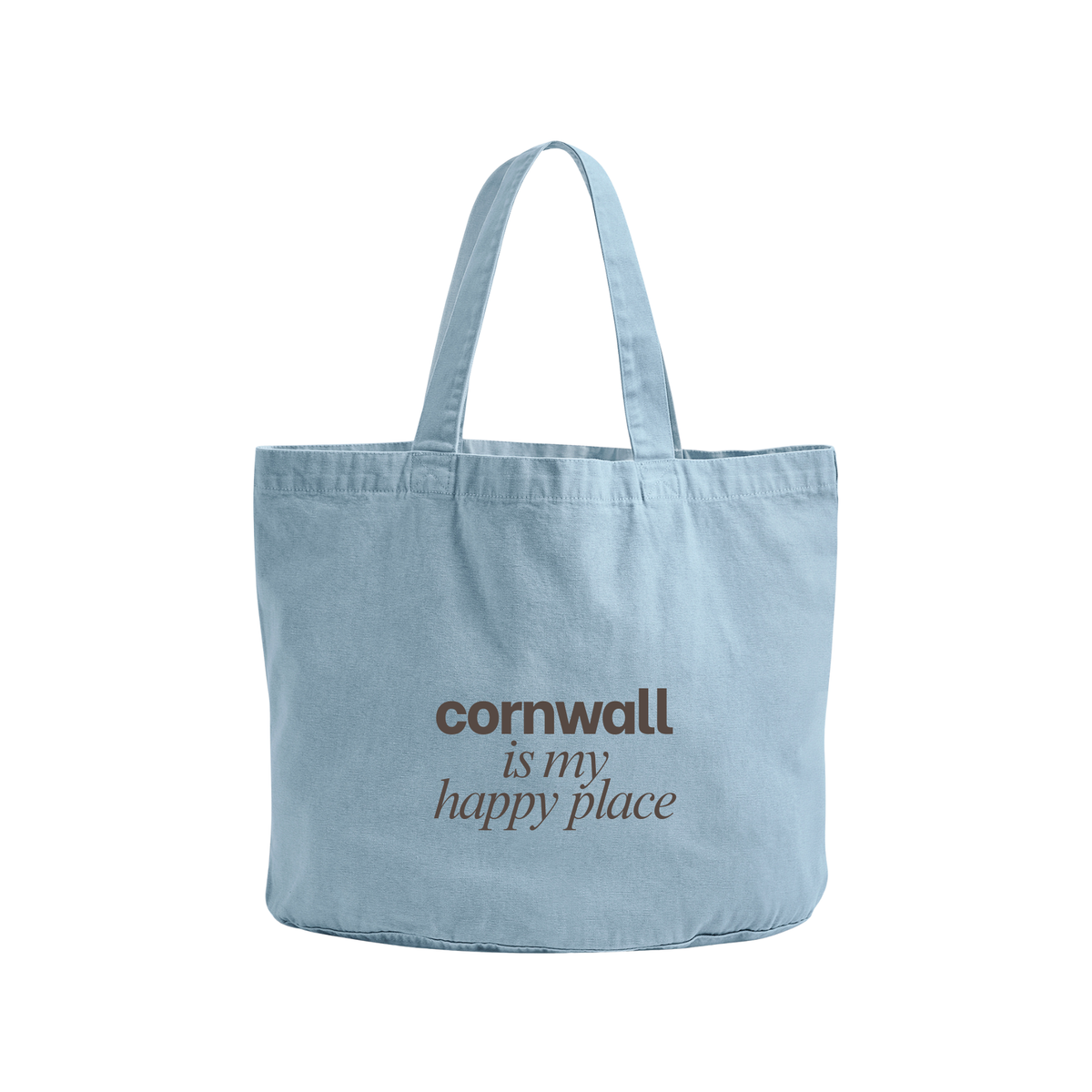 A light blue canvas tote bag with the text 'cornwall is my happy place' printed in brown on the front, set against a plain white background.